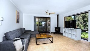A modern living room with a grey sofa, a wooden coffee table, a TV, and a fireplace.