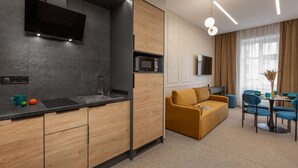 A modern kitchen with a built-in microwave, a sink, and a flat-screen TV mounted above it. - Jam Apartments (Lviv)