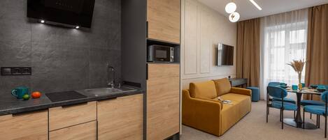A modern kitchen with a built-in microwave, a sink, and a flat-screen TV mounted above it.