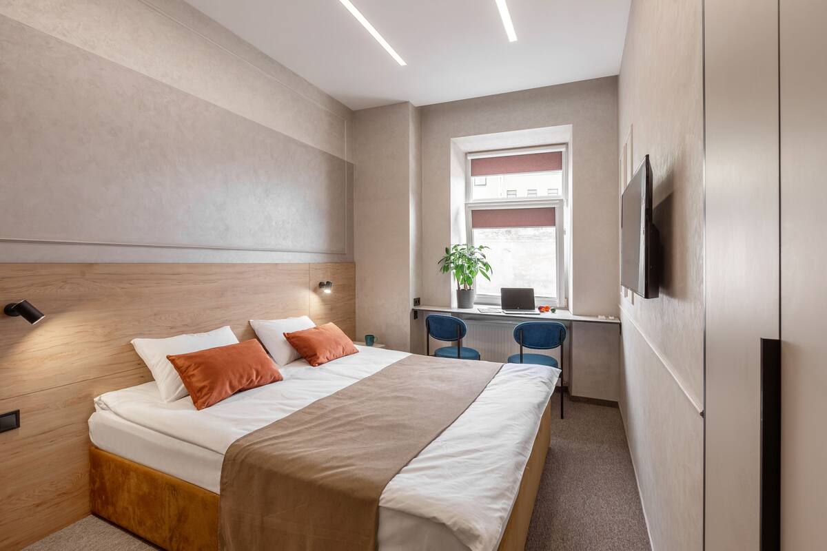 A modern hotel room with a bed, desk, and TV.