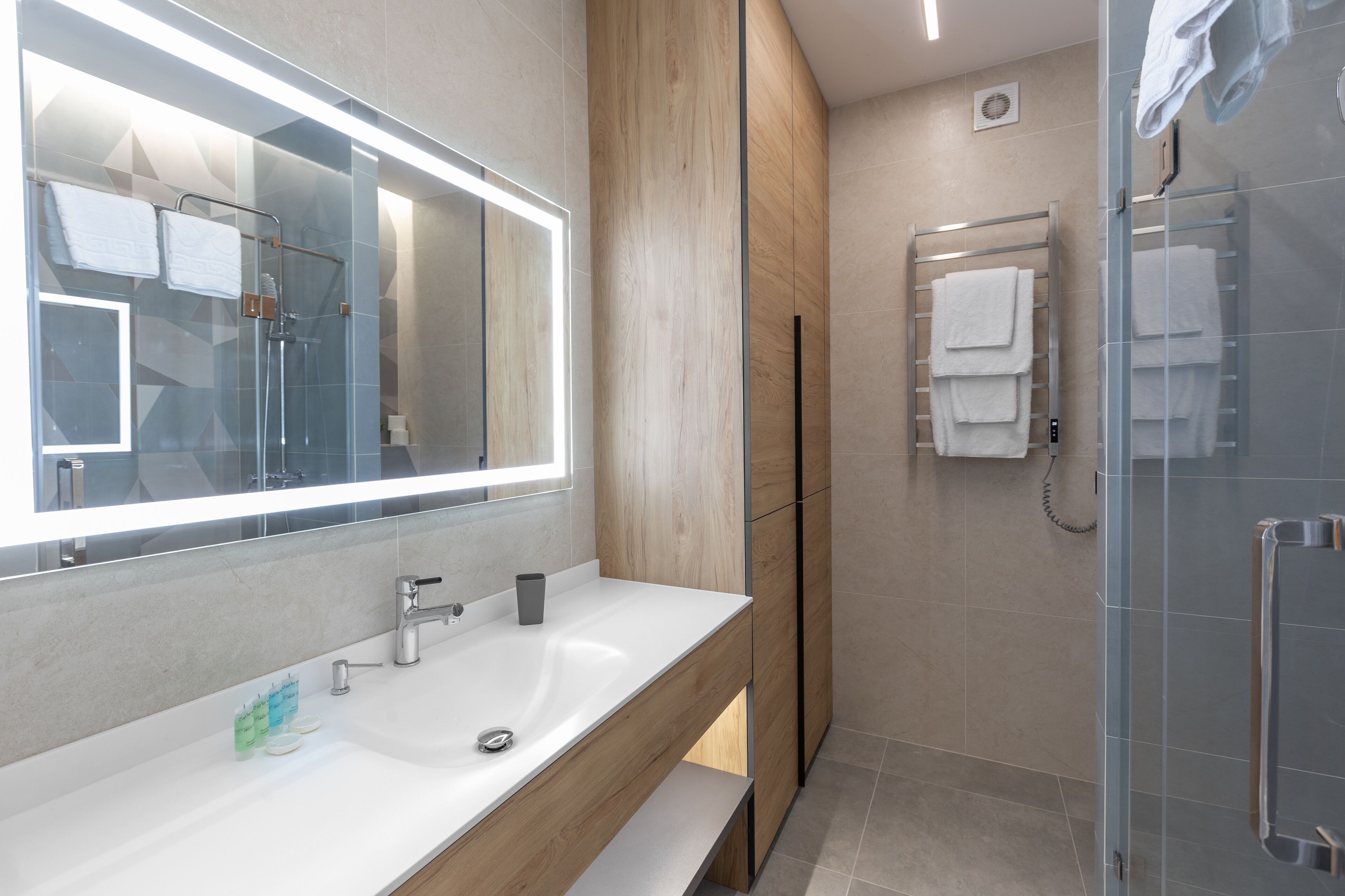 Une salle de bain moderne avec un grand miroir, un lavabo et une douche à parois de verre.