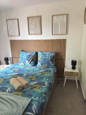 Un dormitorio con cama, mesita de noche, lámpara y decoración en la pared.