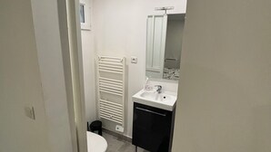 Et badeværelse med toilet, vask, spejl og håndklædestang.