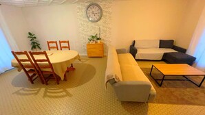 A compact living space with a dining table, chairs, a sofa, a small coffee table, and a clock on the wall. - Maison avec piscine proche des plages (Friville-Escarbotin)