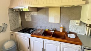 A kitchen with a stove, sink, cabinets, and a tiled floor. - Maison avec piscine proche des plages (Friville-Escarbotin)