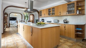 A spacious kitchen with wooden cabinets, a central island with fruit, and a modern stove. - Central Lido Apartment by Homie (Funchal)