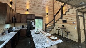 A modern kitchen with wooden walls, a marble countertop, and a built-in refrigerator. - The Beautiful Moonlight Dream Cabin in Broken Bow is STUNNING! (Broken Bow)