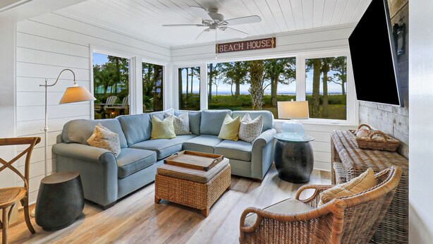 A spacious living area with a large sectional sofa, wicker furniture, and a ceiling fan.