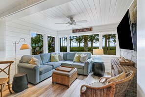 A spacious living area with a large sectional sofa, wicker furniture, and a ceiling fan.