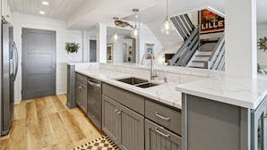 A modern kitchen with a marble countertop, stainless steel sink, and gray cabinetry.