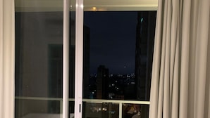 A hotel room with a bed, a desk, and a balcony with curtains. - Luz 1109 (São Paulo)