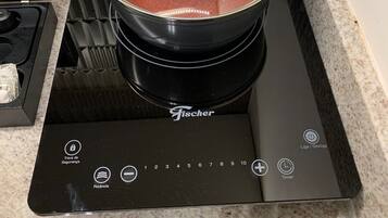 Una cocina con tope de inducción negro y una olla roja encima.