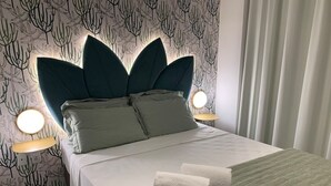 A neatly made bed with a unique headboard, two bedside lamps, and a patterned wallpaper. - Luz 1109 (São Paulo)