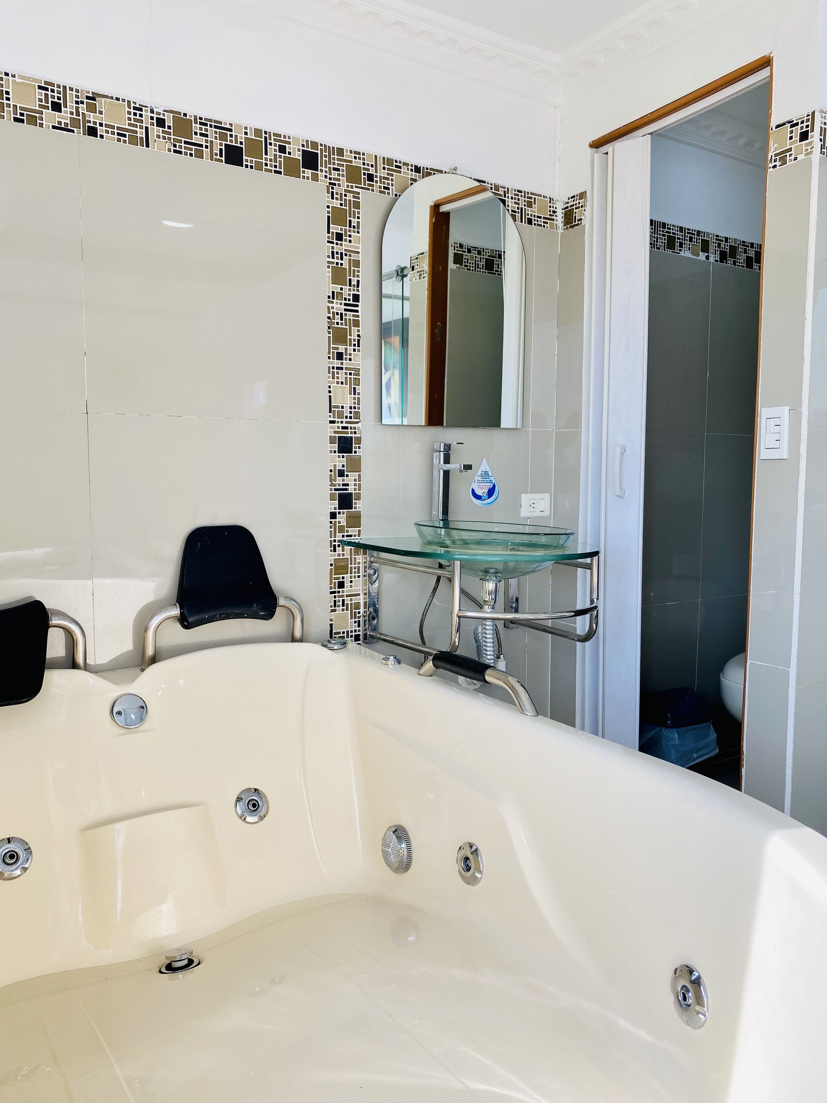 Une salle de bain moderne avec une grande baignoire, un lavabo entouré de parois en verre et un miroir au-dessus du lavabo.