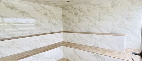 A bathroom with marble walls and wooden flooring.