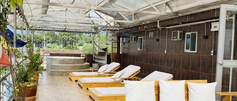A covered outdoor lounge area with wooden beds and potted plants.