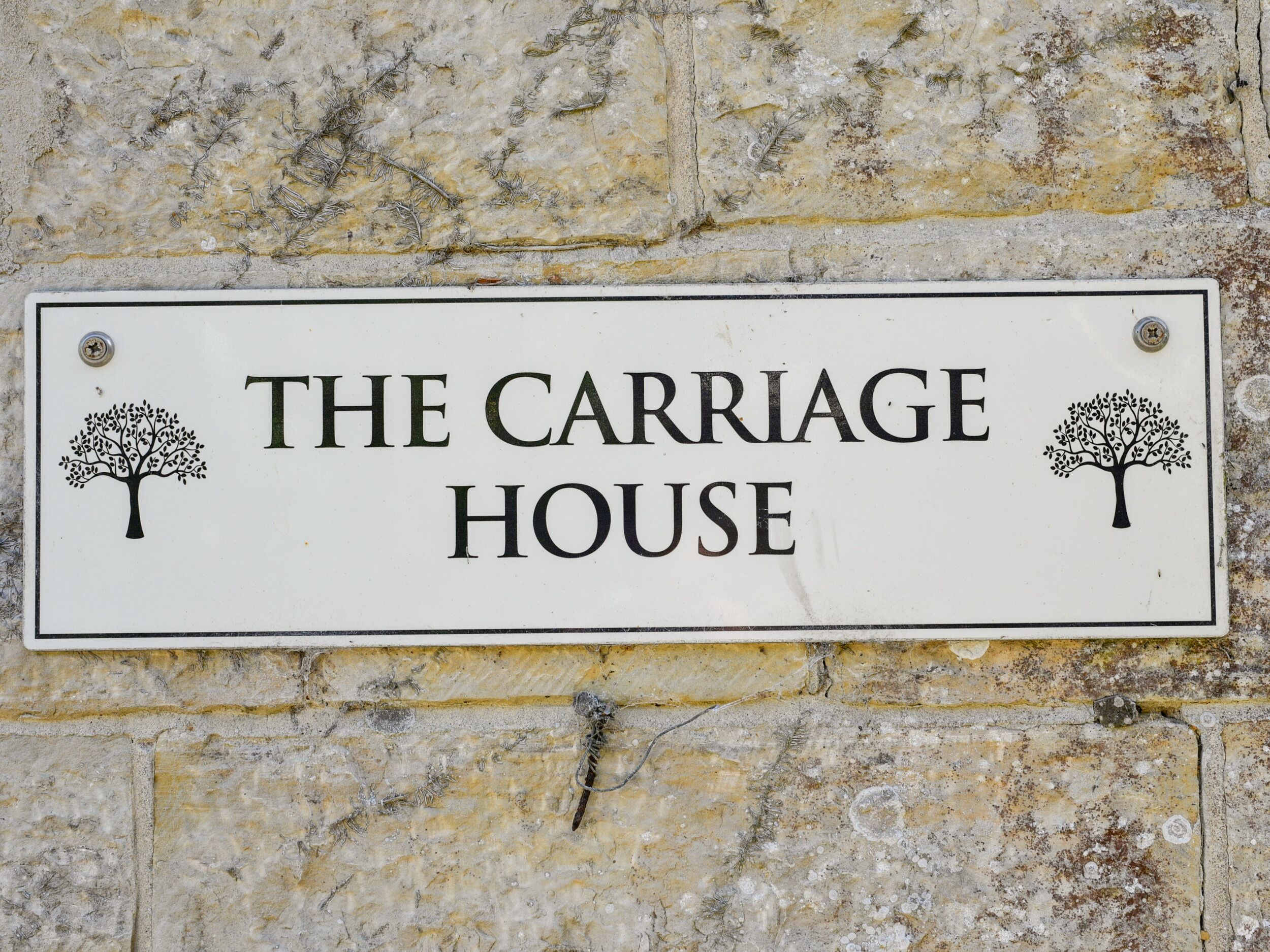 Schild für "The Carriage House" mit zwei Baum-Designs an jeder Seite.