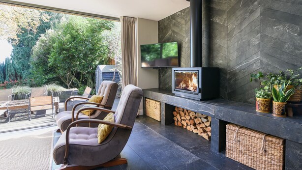 A modern living room with a fireplace, comfortable seating, and a TV. - The Carriage House (Lyme Regis)