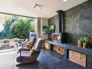 A modern living room with a fireplace, comfortable seating, and a TV. - The Carriage House (Lyme Regis)