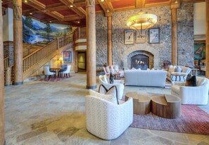 A spacious lobby with a stone fireplace, comfortable seating, and a staircase leading to an upper level. - Mountain Modern Beaver Creek Village Condo, Ski-In and Out, w/ Hot Tub and Views (Beaver Creek)