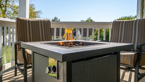 A patio with a gas fire pit table and two striped chairs. - Cozy and Close to Kings Island (Kings Mills)