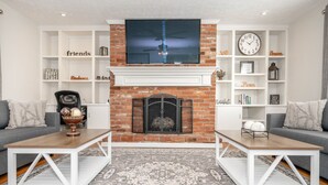 A living room with a fireplace, two sofas, a coffee table, and a TV mounted above the fireplace. - Cozy and Close to Kings Island (Kings Mills)