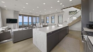 A modern kitchen with a central island, built-in appliances, and large windows offering ocean views.