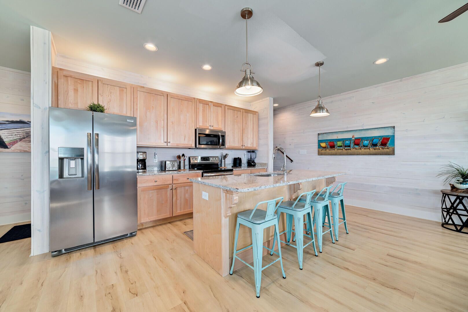 A modern kitchen with wooden cabinets, stainless steel appliances, and a central island with bar stools.