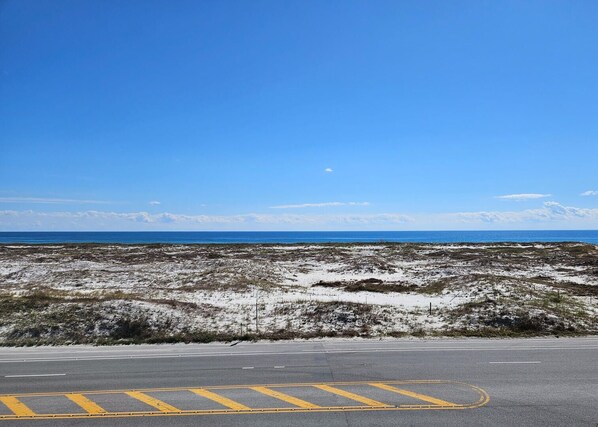 A road with a parking area and a view of the ocean.