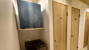 A hallway with wooden doors, a small appliance unit, and a mounted television. - Sho inn MINIMAL HOTEL (Otaru)
