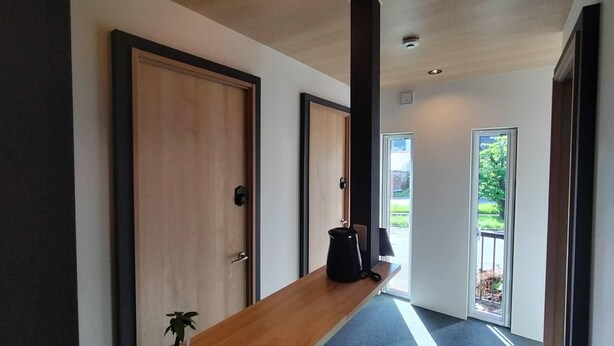 A hallway with wooden doors, a bench, and a potted plant. - Sho inn MINIMAL HOTEL (Otaru)