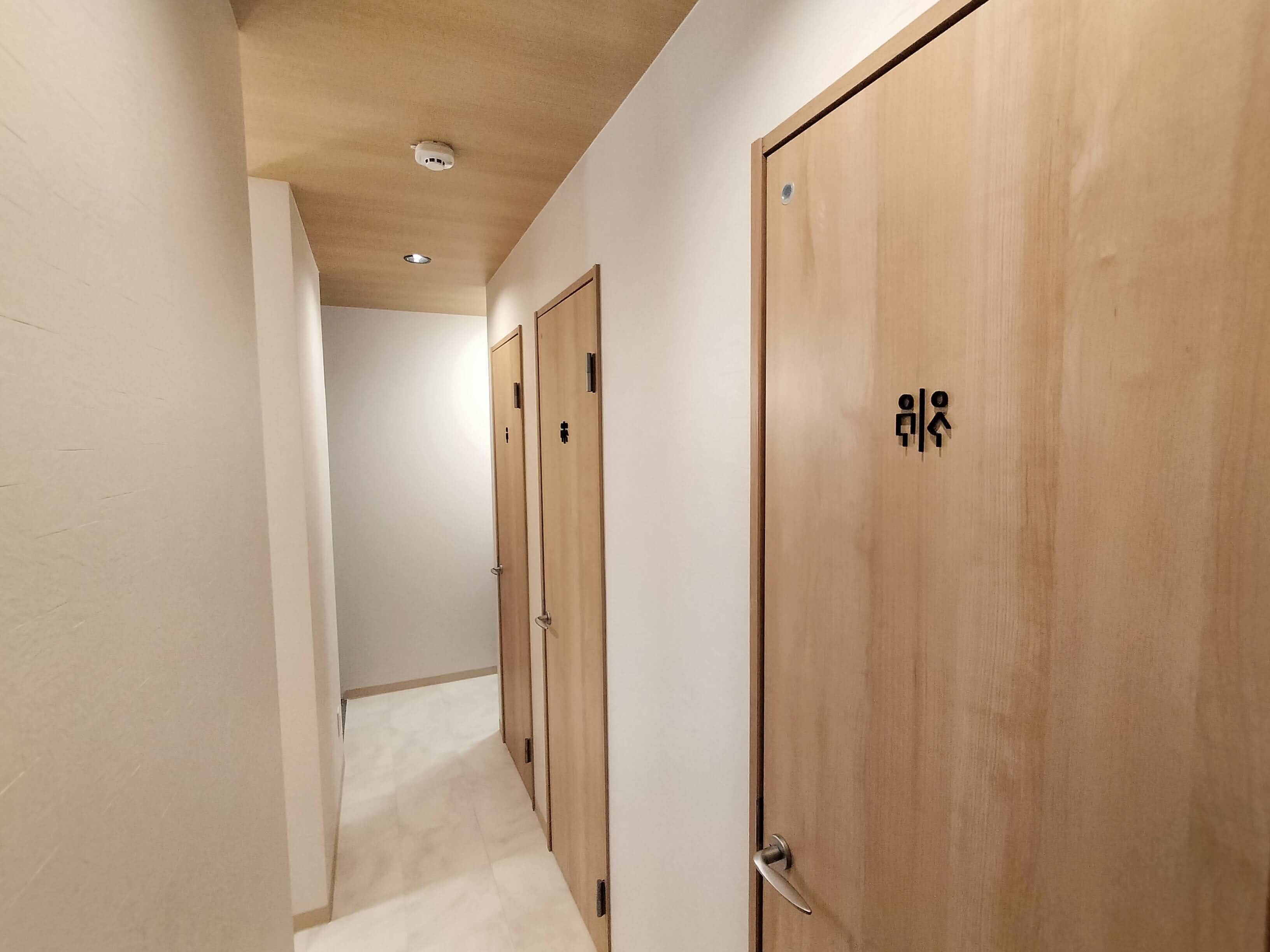 A hallway with wooden doors, each marked with a symbol indicating a specific room function.