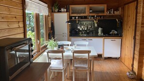 Cocina compacta con armarios de madera, una mesa de comedor con sillas, un microondas y una ventana con vistas a zonas verdes.