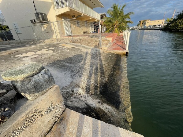 Waterfront property with a concrete retaining wall and adjacent building featuring a balcony.