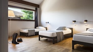 Un dormitorio moderno con dos camas individuales, una lámpara de pie y un ventanal con vistas a zonas verdes.