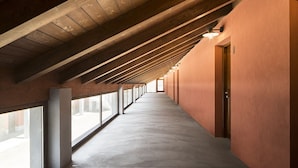 Un largo pasillo con techo alto y vigas de madera, que conduce a una puerta al final.