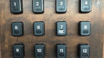 Un panel de madera con doce botones numerados, probablemente para selección de habitaciones o funciones de control.