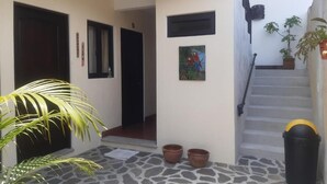 A clean, modern entrance with a stone floor, a staircase, and potted plants. - Posada Maya  (Antigua Guatemala)
