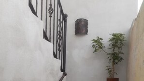 A staircase with a metal railing, a potted plant, and a wall-mounted object. - Posada Maya  (Antigua Guatemala)