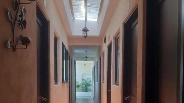 A corridor with a skylight, doors on both sides, and a view into another room. - Posada Maya  (Antigua Guatemala)