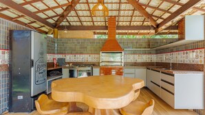 Una cocina con una mesa y sillas de madera, un horno de ladrillo y un refrigerador.