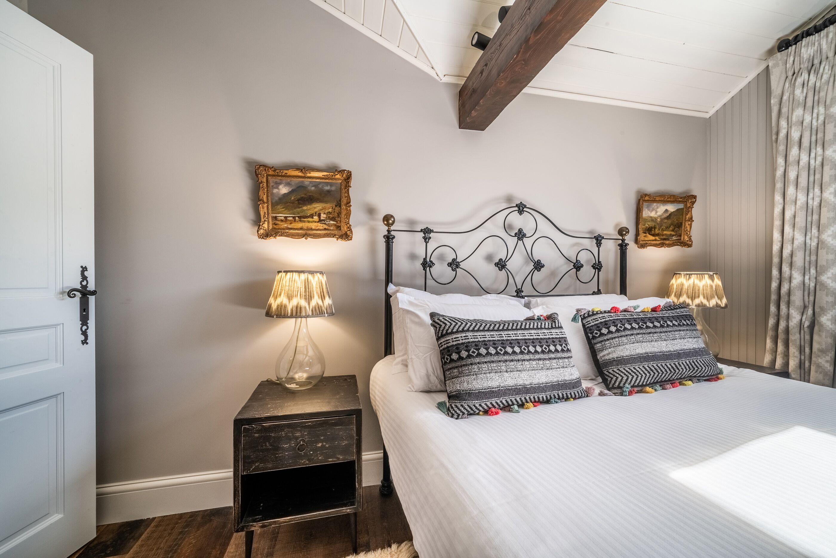 Une chambre à coucher comprenant un lit, deux tables de chevet, deux lampes fixées au mur et deux tableaux encadrés.