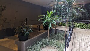 A modern outdoor area with potted plants, a staircase, and a metal railing. - Sunflower Stays (São Paulo)