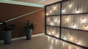 A modern interior with a wooden slat wall, potted plants, and a series of hanging light fixtures. - Sunflower Stays (São Paulo)