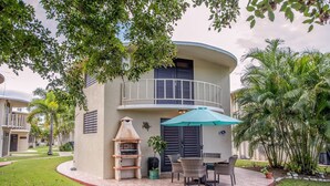 A two-story building with a balcony, outdoor seating area, and a barbecue grill. -  EcoMar Rentals Villa (Cabo Rojo)