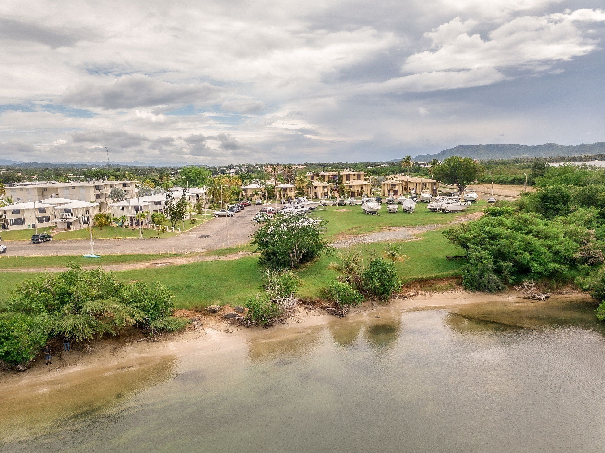 A coastal resort with multiple bungalow-style buildings, a parking area, and a beach.