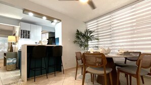 A modern kitchen with a bar area, dining table, and chairs. -  EcoMar Rentals Villa (Cabo Rojo)