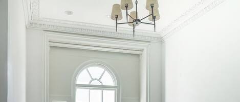 A staircase with a wooden handrail leading to a white door with a large arched window.