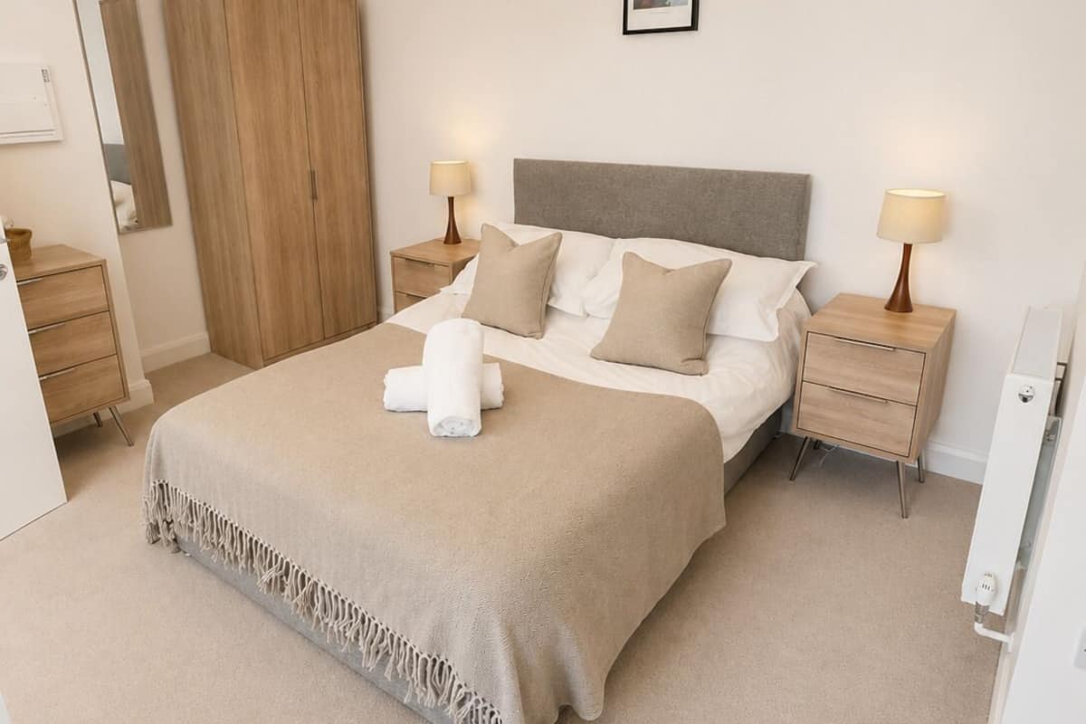 Une chambre à coucher comprenant un lit, des tables de chevet, une armoire, un luminaire suspendu et un tableau encadré accroché au mur.