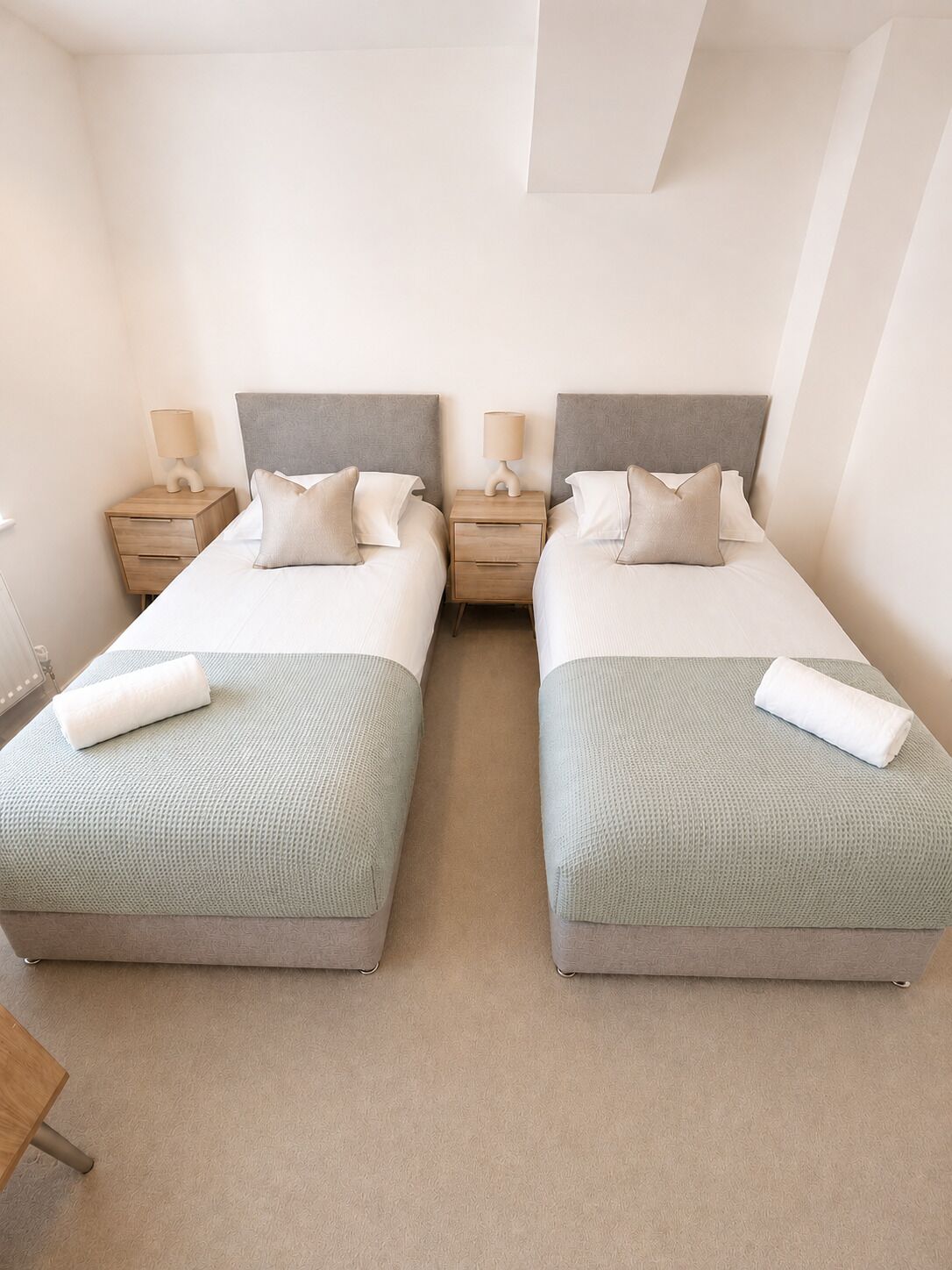 Une chambre double avec deux lits, chacun étant équipé d’une table de chevet, d’une lampe et d’une serviette.